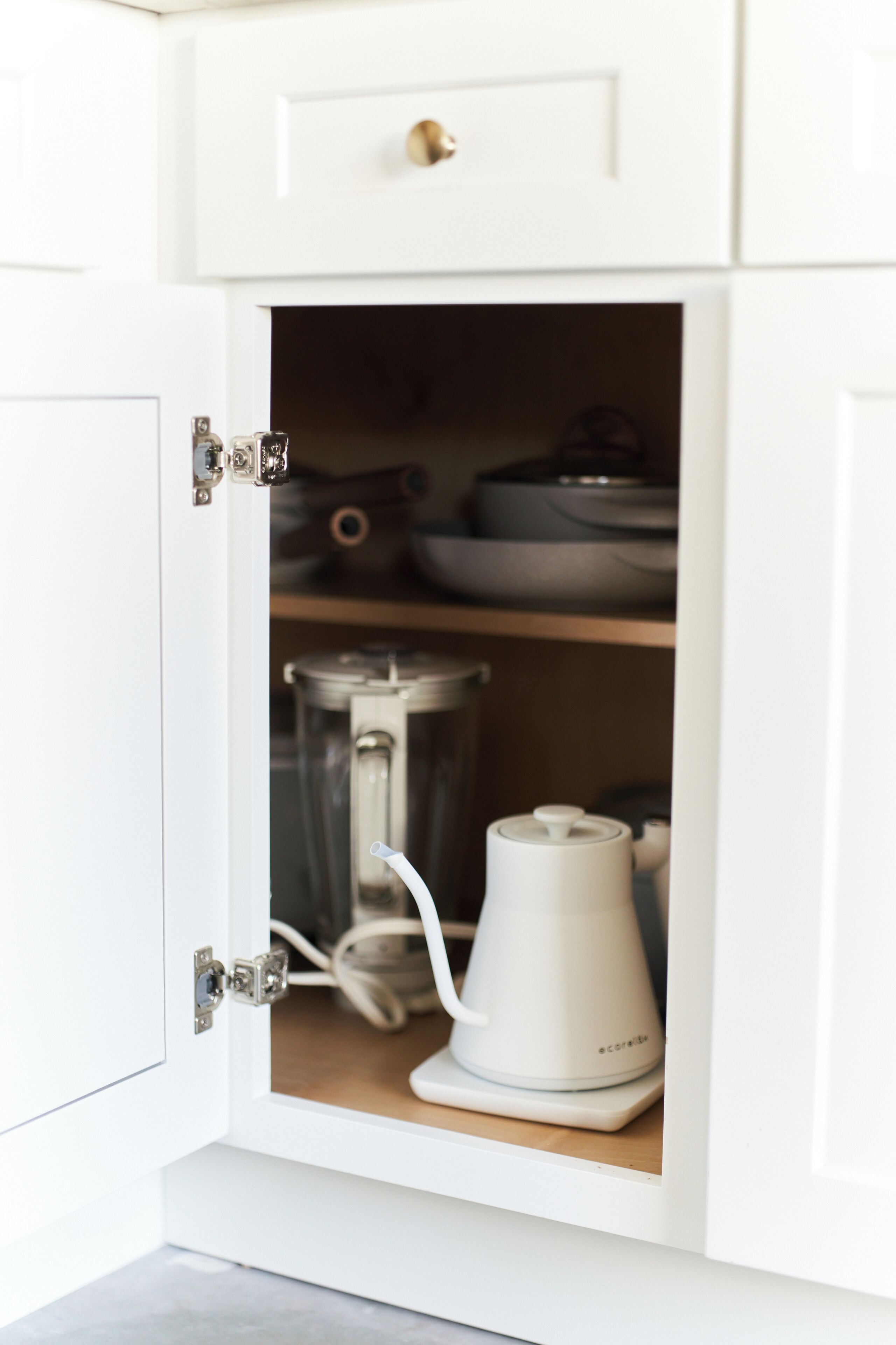 A white kitchen cabinet with a built-in coffee maker and a blender.
