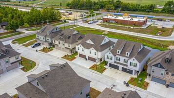 A residential area with modern houses, a commercial building, and a road with vehicles.
