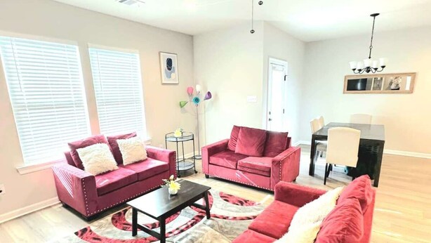 A living room with two red sofas, a coffee table, and a ceiling fan. - Serene Oasis for Deep Relaxation Near LSU - CL5628 (Baton Rouge)