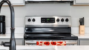 A kitchen with a stainless steel stove, a digital clock, and a coffee maker.