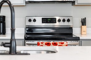A kitchen with a stainless steel stove, a digital clock, and a coffee maker. - Serene Oasis for Deep Relaxation Near LSU - CL5628 (Baton Rouge)