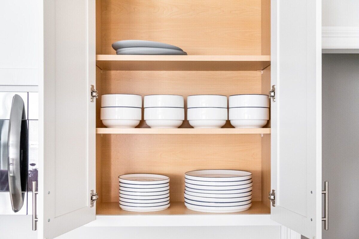 A kitchen cabinet with multiple shelves, each holding bowls and plates.