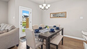A dining area with a table set for four, chairs, a chandelier, and a door leading outside. - Serene Oasis for Deep Relaxation Near LSU - CL5628 (Baton Rouge)