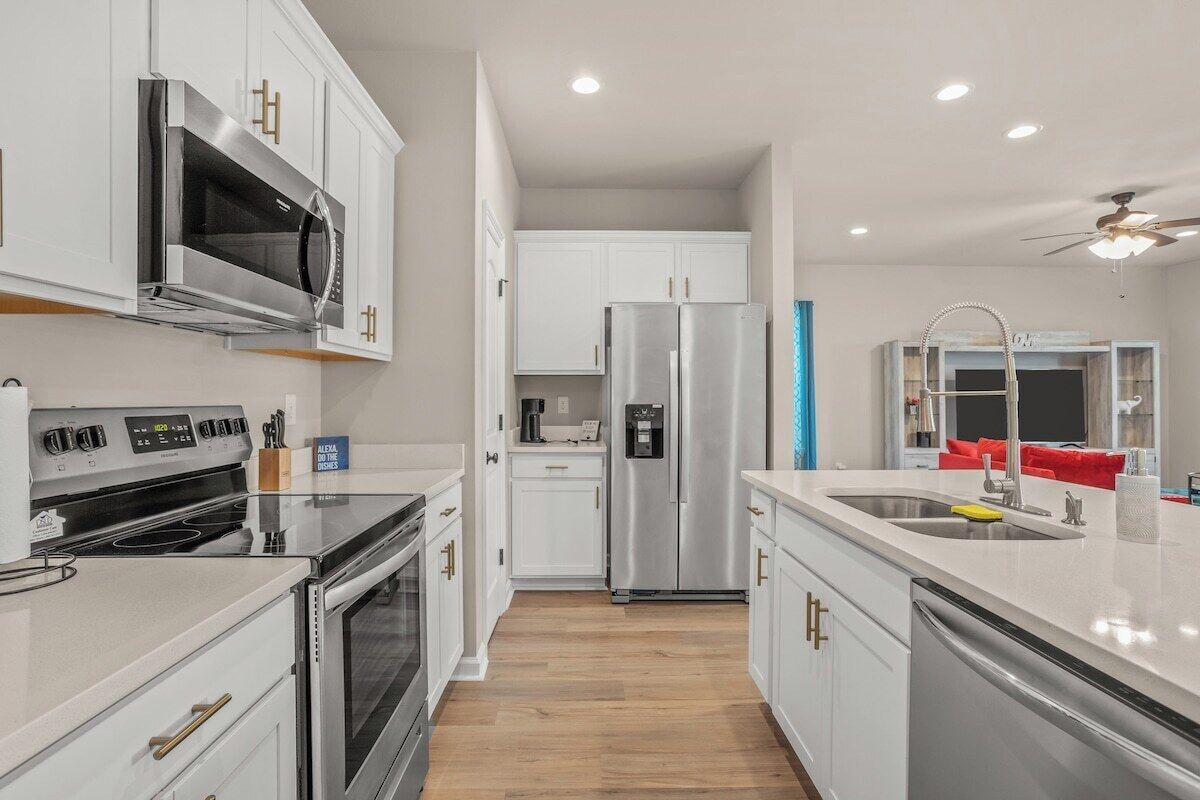 Una cocina moderna con armarios blancos, electrodomésticos de acero inoxidable y una isla central con pileta.
