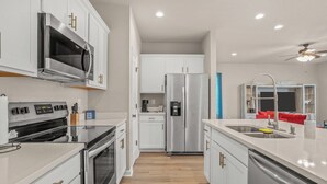 A modern kitchen with white cabinetry, stainless steel appliances, and a central island with a sink.