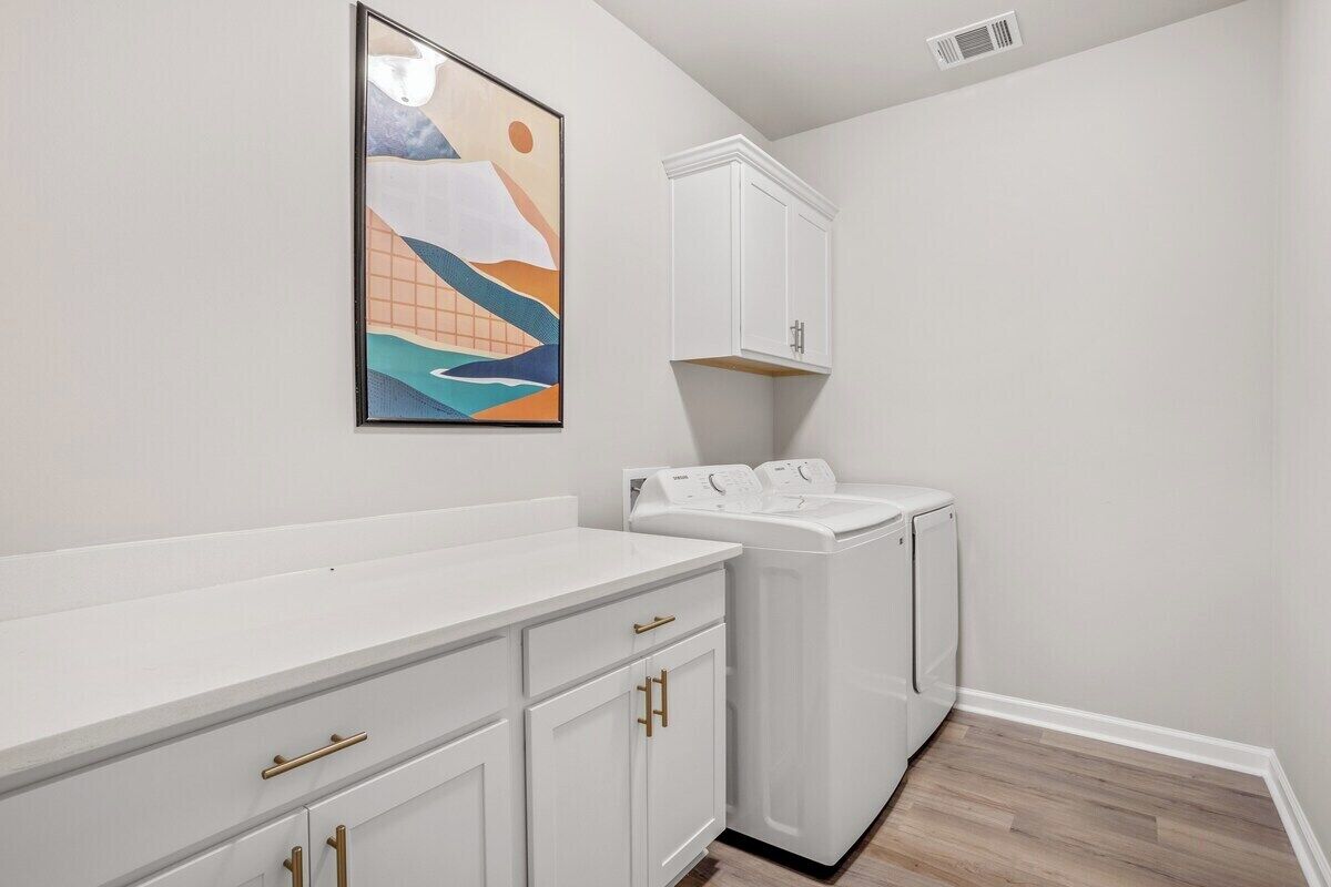 A laundry room with a white countertop, a washing machine, and a cabinet.