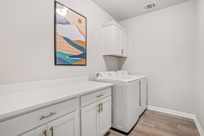 A laundry room with a white countertop, a washing machine, and a cabinet. - Serene Oasis for Deep Relaxation Near LSU - CL5628 (Baton Rouge)