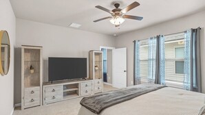 A bedroom with a bed, a television, a ceiling fan, a wardrobe, and a window with curtains. - Serene Oasis for Deep Relaxation Near LSU - CL5628 (Baton Rouge)