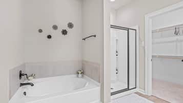 A modern bathroom with a freestanding bathtub, a glass shower enclosure, and a white shower curtain.