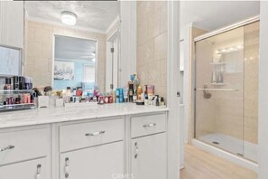Bathroom features a large mirror, glass shower enclosure, and ample countertop space.