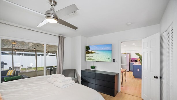 Une chambre d’hôtel moderne dotée d’un grand lit, d’un ventilateur de plafond, d’une télévision et offrant une vue sur la plage.