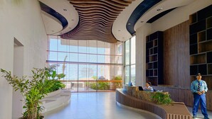 Un espace d’accueil moderne, doté d’un comptoir incurvé, de grandes fenêtres et de plantes d’intérieur.