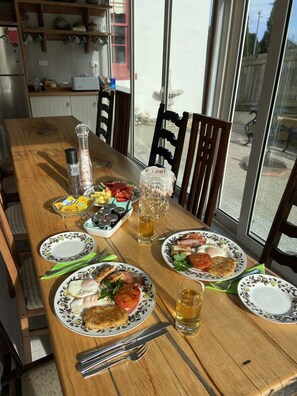 A dining table with plates of food, a pitcher of beer, and condiments. - Poet's Cottage Stanley (Stanley)