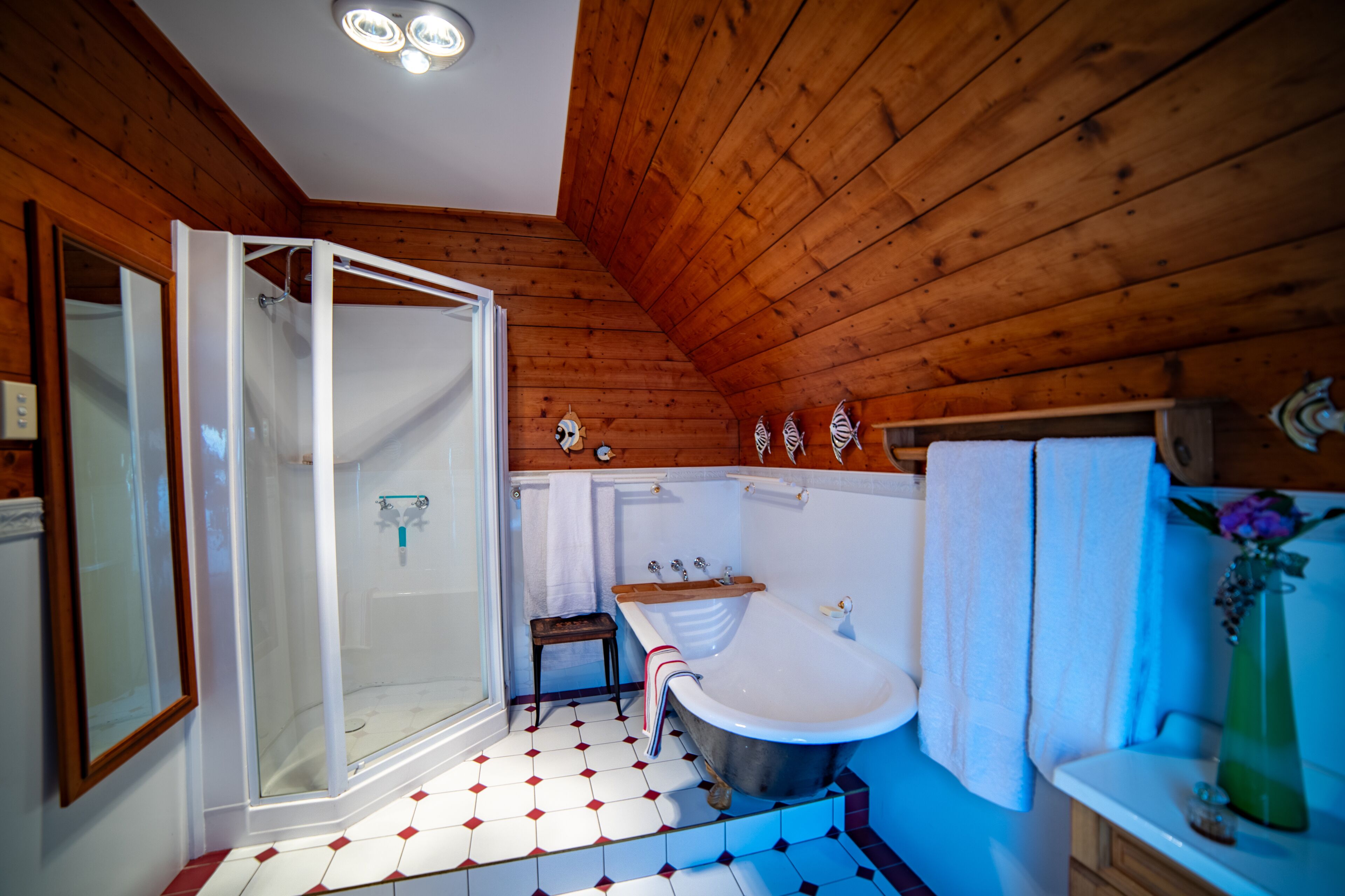 Een houten badkamer in een chalet, met een ruime douche, een badkuip en een klein krukje.