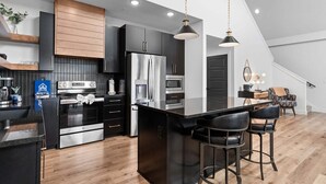 A modern kitchen with a central island, stainless steel appliances, and a bar area with stools. - Lake View Getaway with Hot Tub, Arcade, Indoor Community Pool & Free Silver Dollar Tickets (Hollister)