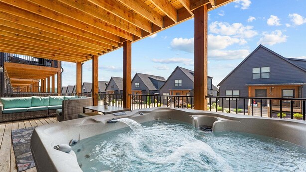 A hot tub area with wooden beams, a sofa, and a view of multiple houses. - Lake View Getaway with Hot Tub, Arcade, Indoor Community Pool & Free Silver Dollar Tickets (Hollister)
