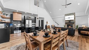 A modern kitchen with a dining area, a fireplace, and a ceiling fan. - Lake View Getaway with Hot Tub, Arcade, Indoor Community Pool & Free Silver Dollar Tickets (Hollister)