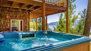 A hot tub with a wooden deck and a view of a lake. - Ski, Swim, Relax at Whitefish Lake | Stunning Views of Whitefish Lake (Whitefish)