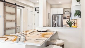 A modern kitchen with white cabinetry, a marble countertop, and a built-in refrigerator.