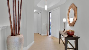 Ein Flur mit einer großen Bambusvase, einem Holztischchen mit einer Lampe und einem Spiegel an der Wand.