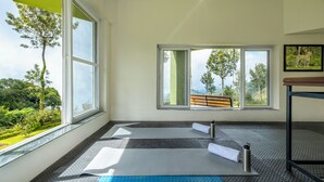 Une pièce dotée de grandes fenêtres, de tapis de yoga et d’une bouteille d’eau.