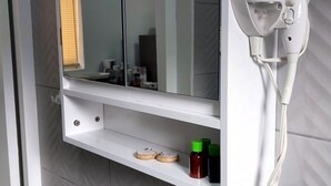 Un botiquín de primeros auxilios sujeto a la pared, junto a un secador de pelo y un espejo.