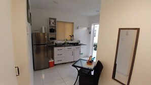 Cocina compacta con refrigerador, pileta y alacenas. Cuenta con una pequeña mesa de comedor y sillas.