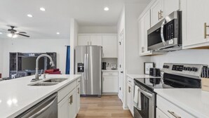A modern kitchen with stainless steel appliances, white cabinetry, and a central island with a sink. - Peaceful Bayou Escape Close to LSU Campus - CL5626 (Baton Rouge)