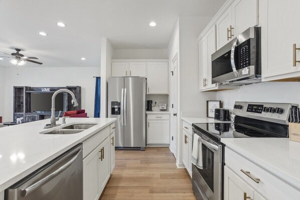 Una cocina moderna con electrodomésticos de acero inoxidable, armarios blancos y una isla central con pileta.