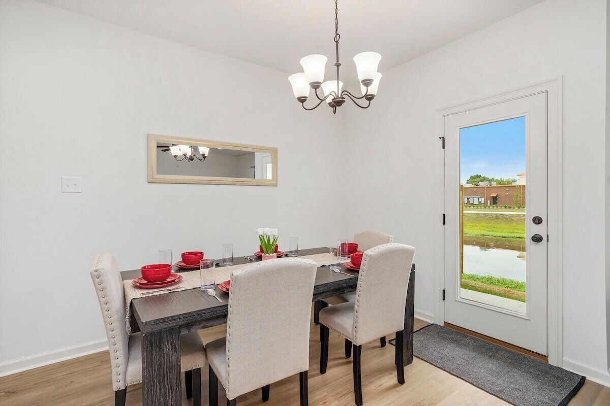 A dining area with a dark wooden table, beige upholstered chairs, and a chandelier.