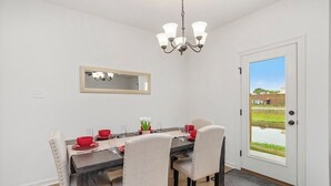 A dining area with a dark wooden table, beige upholstered chairs, and a chandelier. - Peaceful Bayou Escape Close to LSU Campus - CL5626 (Baton Rouge)
