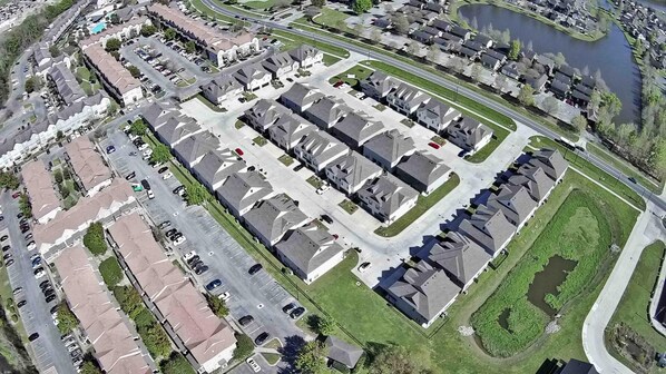 Vue aérienne d’un quartier résidentiel composé de maisons individuelles, une rue principale et une étendue d’eau.