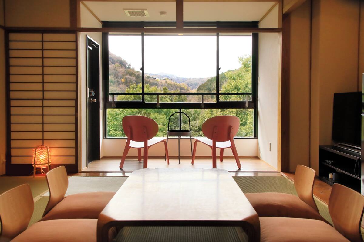 A modern room with a large window, a dining table, and two chairs.