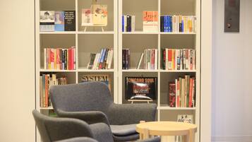 Una biblioteca con estanterías, un sillón gris y una pequeña mesa de madera.