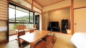 A modern hotel room with a large window, a dining table, a sofa, and a TV. - Hakone Suisen (Hakone)