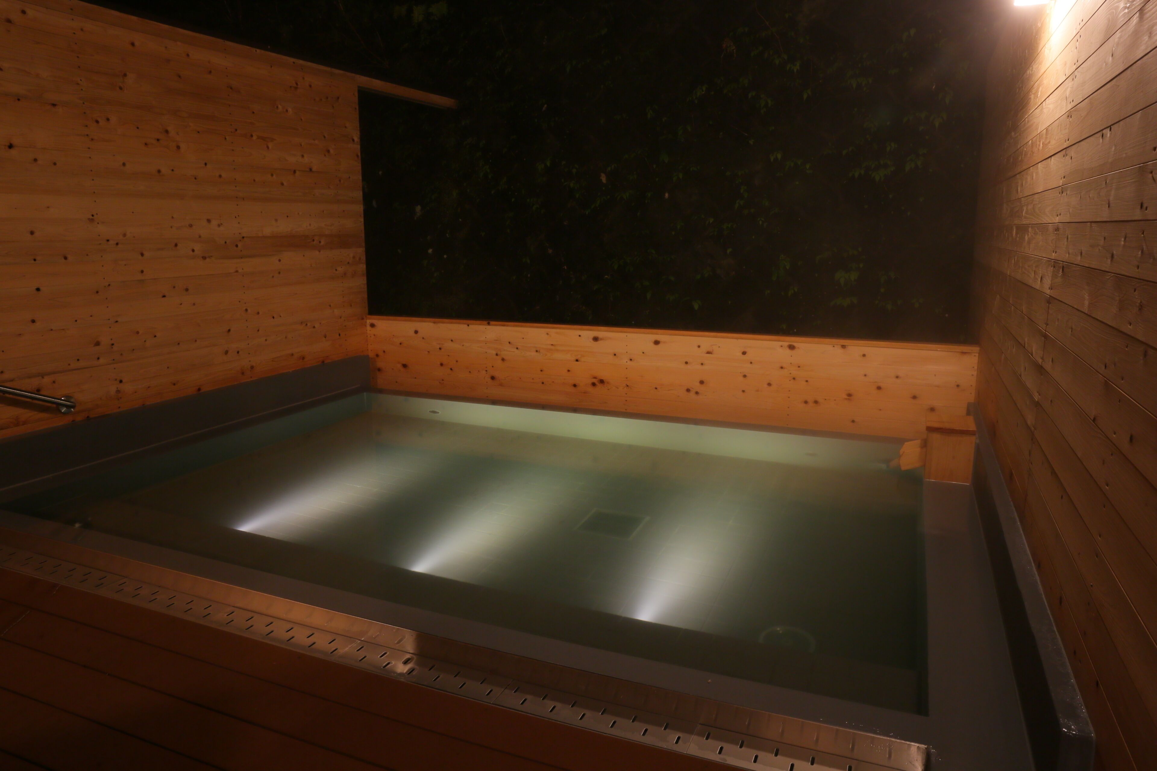 Una sauna de madera con suelo de vidrio, paredes de madera y un banco.