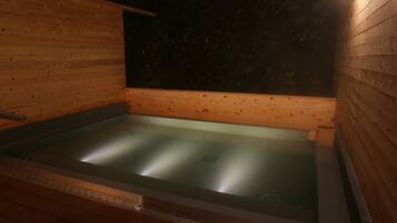 Una sauna de madera con suelo de vidrio, paredes de madera y un banco.