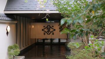 A traditional Japanese building entrance with a wooden door and a sign with Japanese characters.