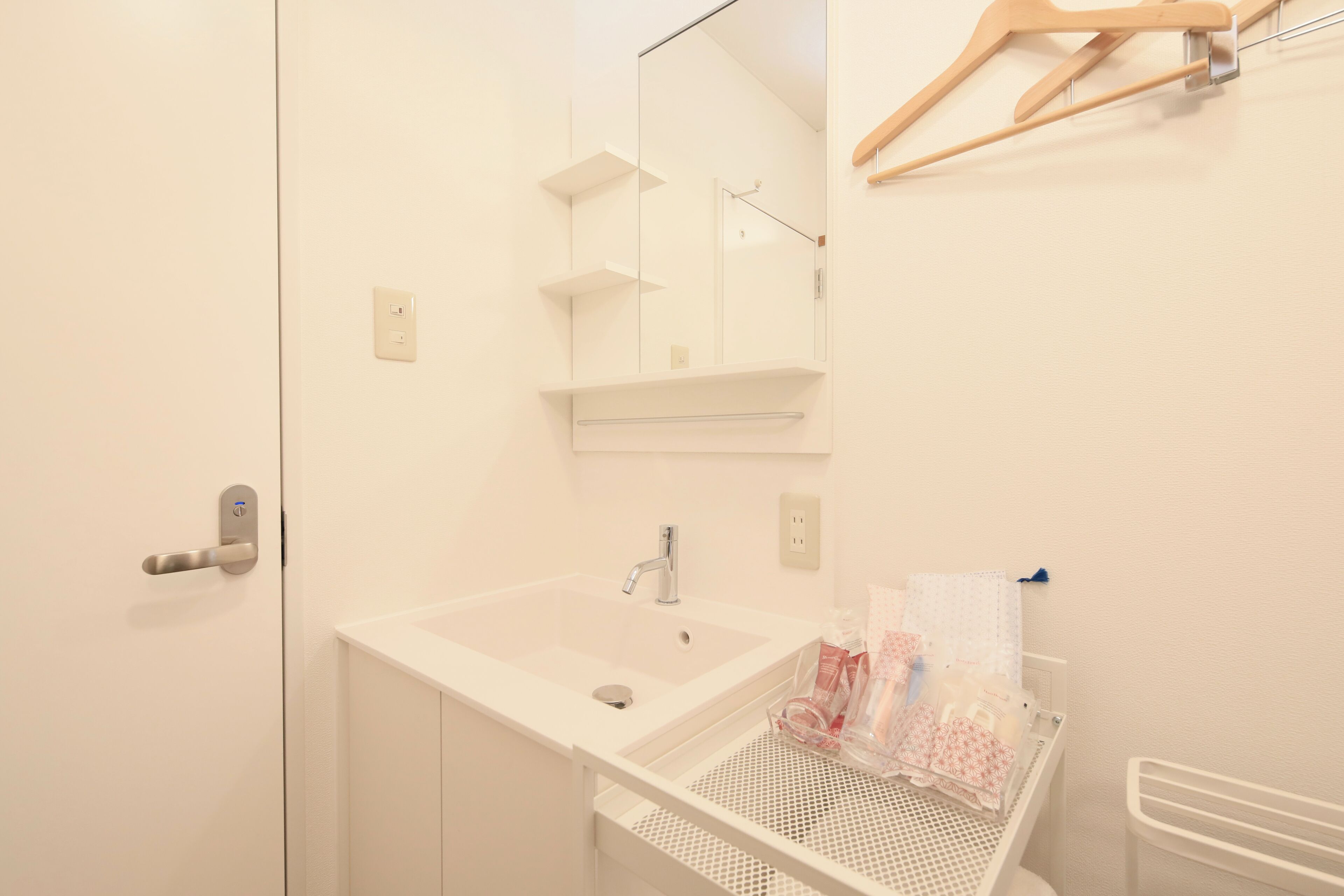 Une salle de bain avec un lavabo blanc, un miroir et des étagères.