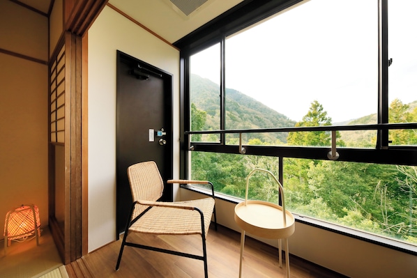 A room with a large window, a chair, a small table, and a door. - Hakone Suisen (Hakone)
