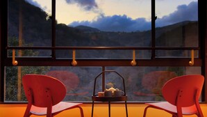 A room with a large window, two red chairs, and a table with a teapot and cups. - Hakone Suisen (Hakone)