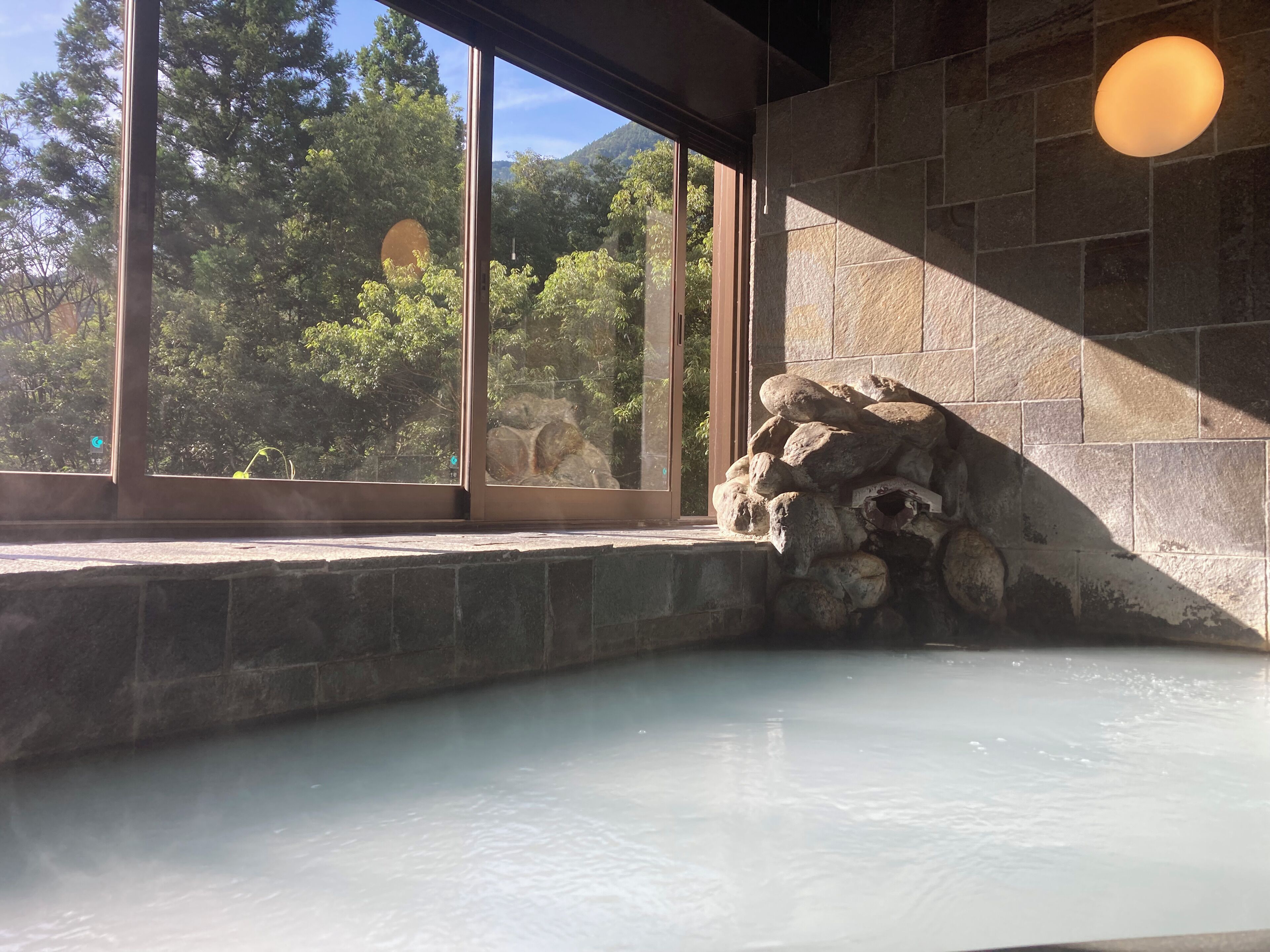 A spa area with a stone wall and a window overlooking a forest.