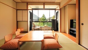 A traditional Japanese-style room with tatami flooring, a low table with cushions, a sliding door, and a view of the outdoors. - Hakone Suisen (Hakone)