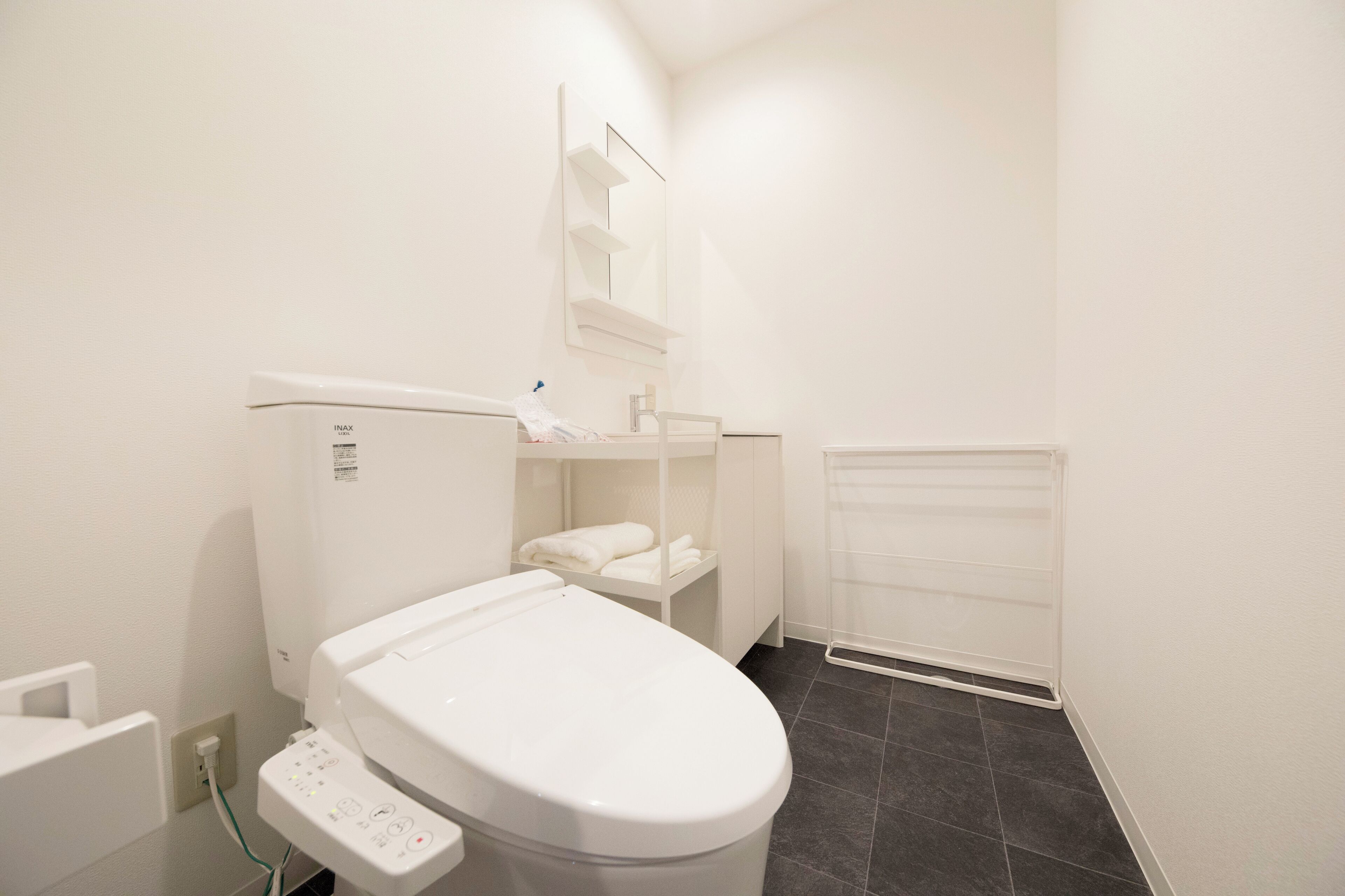 Un baño moderno con inodoro blanco, estante empotrado y perchero.
