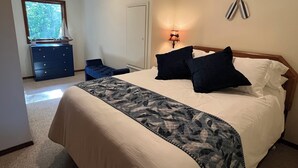 Une chambre à coucher avec un lit, une commode, une lampe et une fenêtre.
