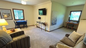Un salon comprenant un canapé, une table à manger et un téléviseur fixé au mur.