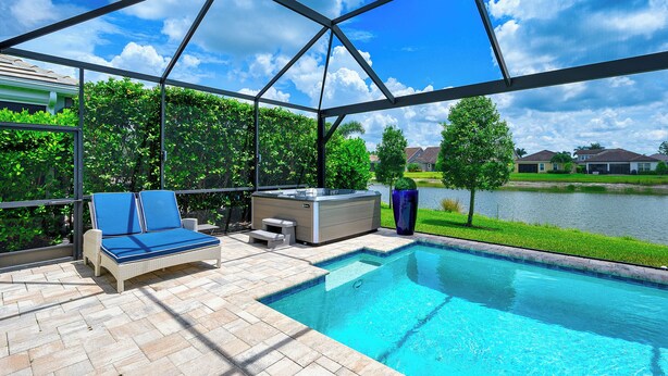 A swimming pool with a hot tub, lounge chairs, and a view of a lake. - Indulge in a lavish home, heated saltwater pool, & spa, near all Naples offers. (Naples)