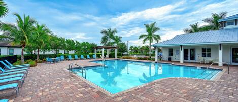 A swimming pool with lounge chairs and palm trees.