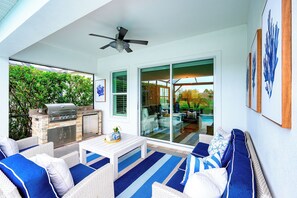 Eine Terrassengruppe im Freien mit Grill, Sitzgelegenheit und Deckenventilator.