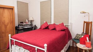 A bedroom with a bed, a desk, a chair, a lamp, and a door.